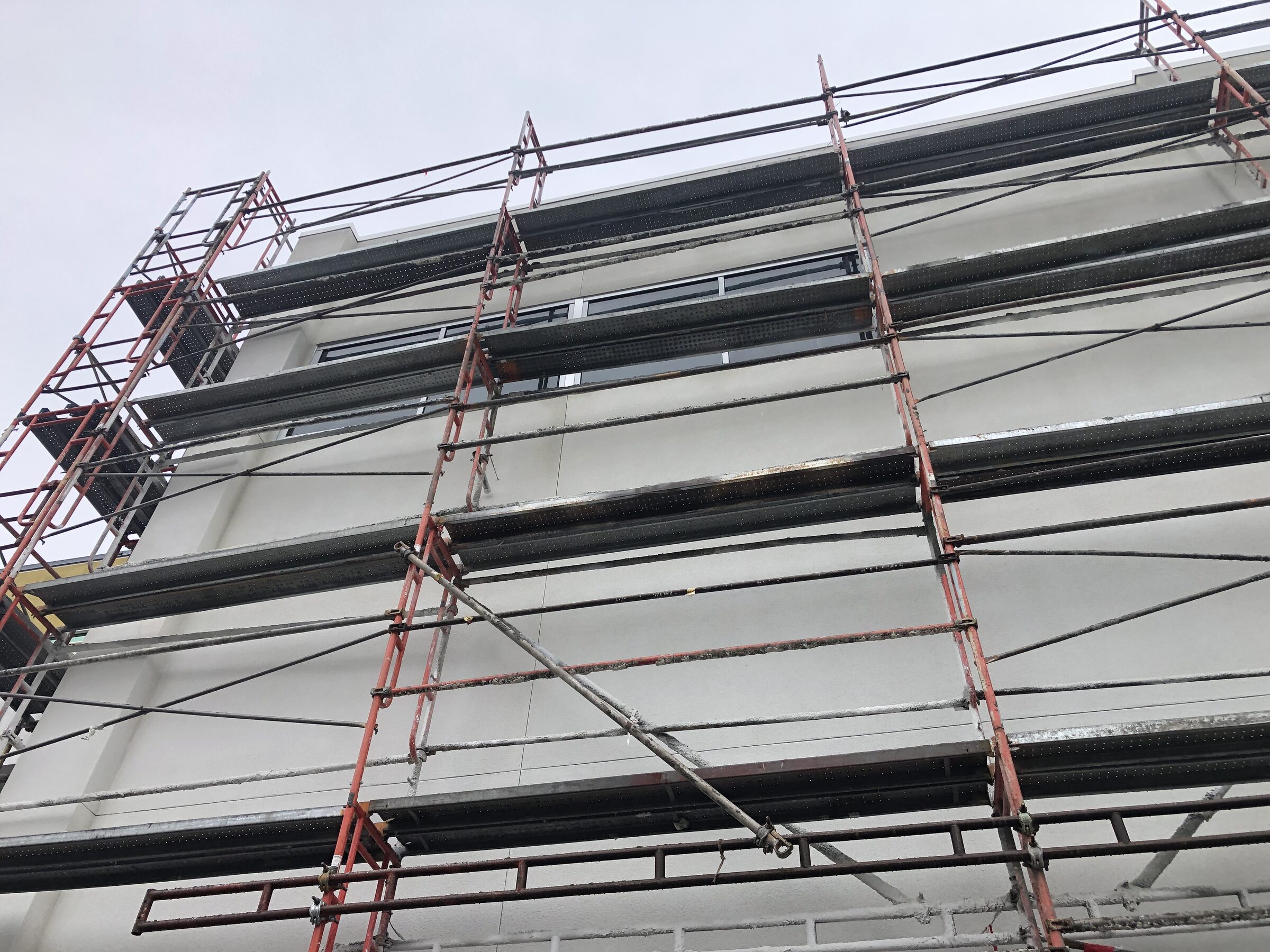 Building facade scaffolding with stucco progress