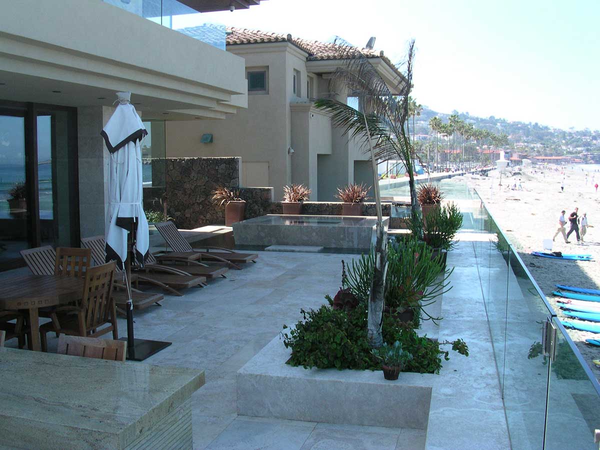Oceanfront patio with glass railing and beach view